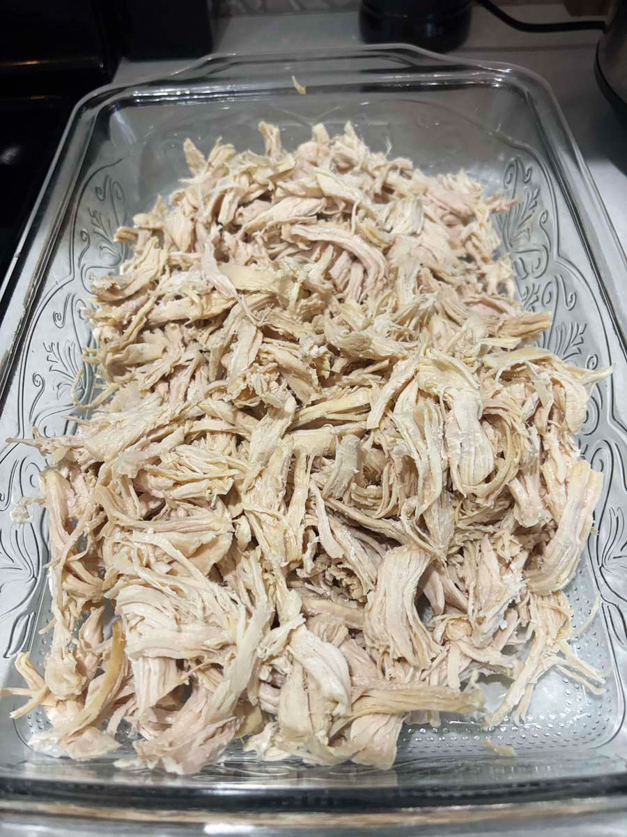 glass casserole dish with pulled chicken in it